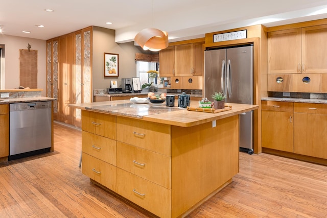 kitchen featuring stainless steel appliances, a center island, pendant lighting, and light wood-type flooring