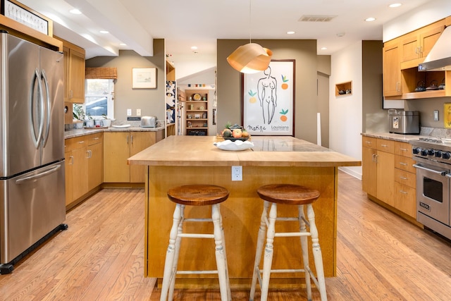 kitchen featuring a kitchen island, pendant lighting, a kitchen bar, stainless steel appliances, and light wood-type flooring