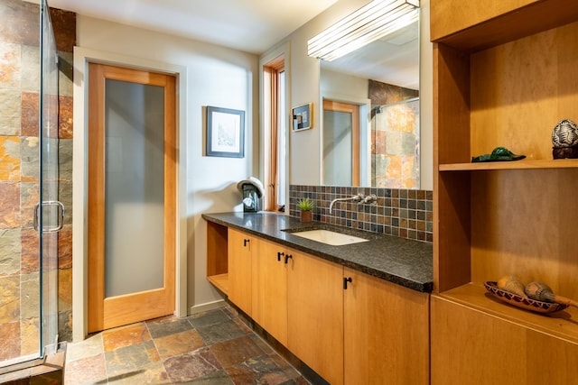 bathroom with vanity, a shower with shower door, and backsplash