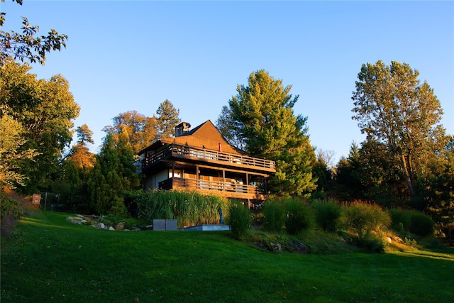 back of property featuring a wooden deck and a yard