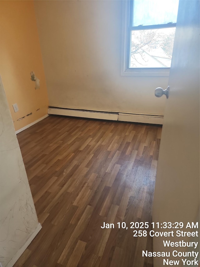 spare room with a baseboard radiator and dark hardwood / wood-style flooring