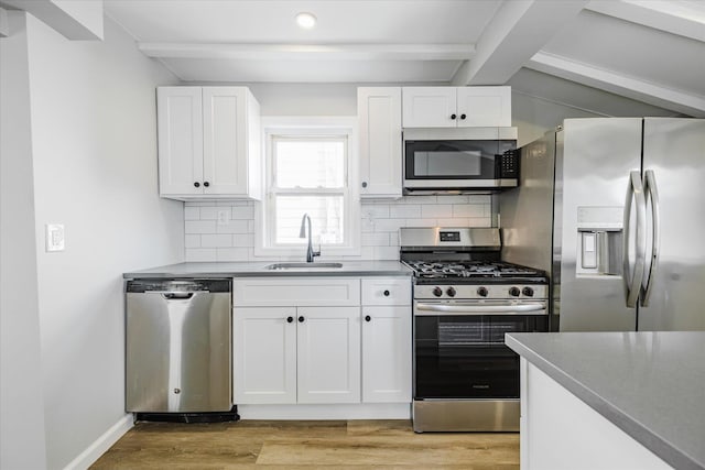 kitchen with sink, appliances with stainless steel finishes, beam ceiling, light hardwood / wood-style floors, and white cabinets