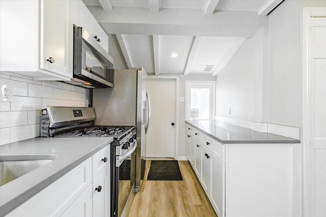 kitchen featuring appliances with stainless steel finishes, beam ceiling, light hardwood / wood-style flooring, and white cabinets