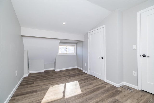 interior space with dark hardwood / wood-style flooring and vaulted ceiling