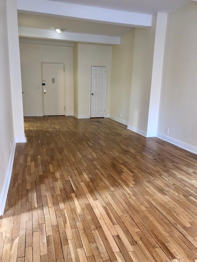 unfurnished room featuring wood-type flooring and beam ceiling