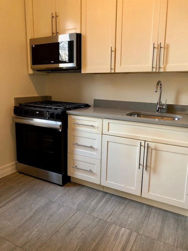 kitchen featuring sink, white cabinets, and gas range oven