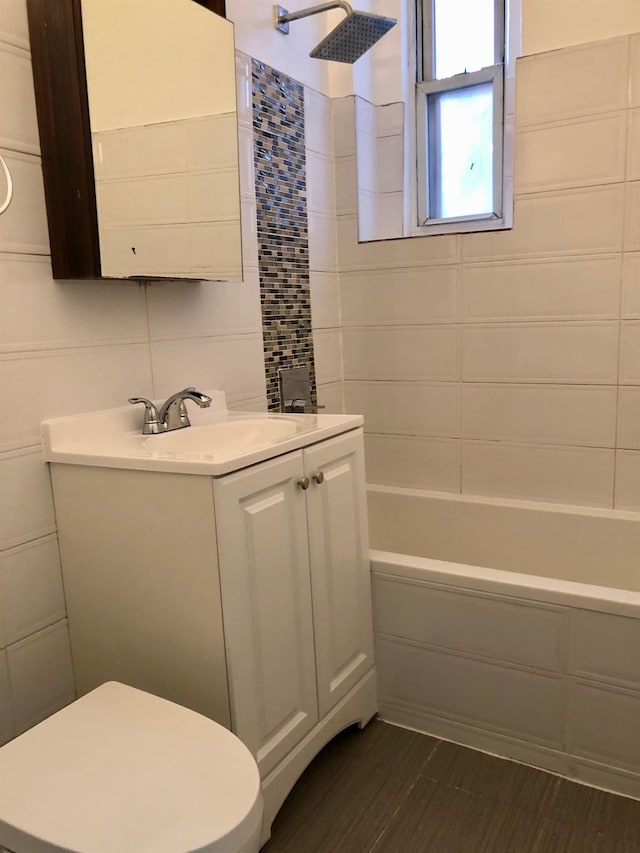 full bathroom with vanity, toilet, tile walls, and tiled shower / bath