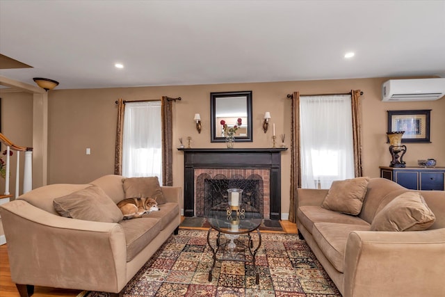 living room with hardwood / wood-style flooring, a brick fireplace, and a wall mounted air conditioner