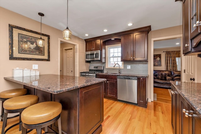 kitchen with stainless steel appliances, sink, a kitchen breakfast bar, and dark stone counters