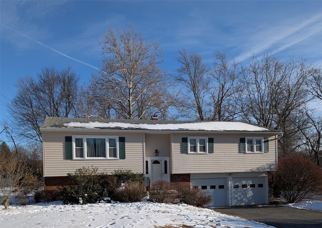 split foyer home with aphalt driveway, an attached garage, and brick siding