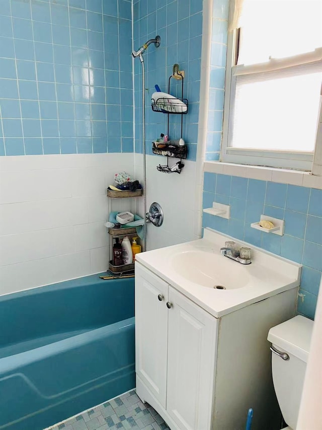 full bathroom with vanity, tiled shower / bath, tile walls, and toilet