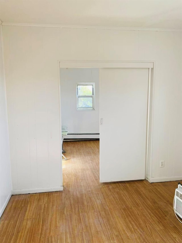 spare room with ornamental molding, a baseboard heating unit, and light hardwood / wood-style flooring