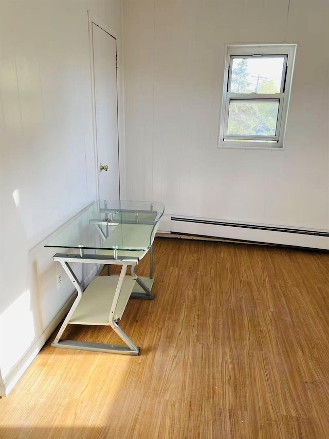 unfurnished dining area featuring a baseboard radiator and hardwood / wood-style floors