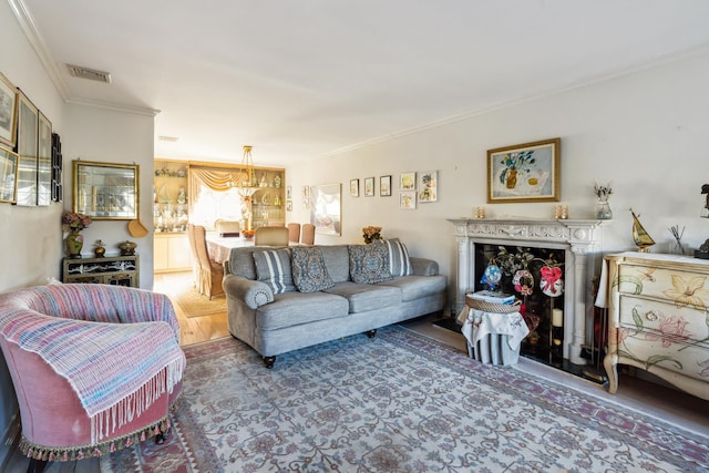 living area featuring visible vents, wood finished floors, and ornamental molding