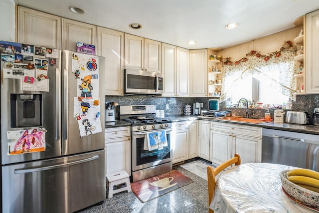 kitchen with open shelves, dark countertops, granite finish floor, appliances with stainless steel finishes, and a sink