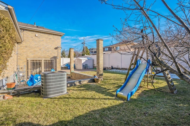 view of yard featuring a fenced backyard, a storage unit, an outdoor structure, central air condition unit, and a playground