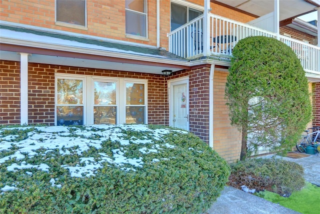 snow covered property entrance with a balcony