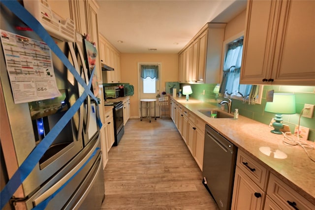 kitchen with light brown cabinetry, sink, decorative backsplash, black appliances, and light hardwood / wood-style flooring