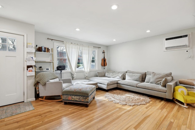 living room with a wall mounted air conditioner and light hardwood / wood-style flooring