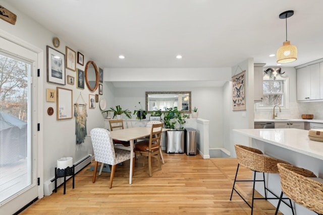 dining space with a baseboard radiator, sink, and light wood-type flooring