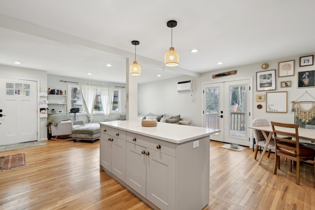 kitchen featuring french doors, white cabinetry, a wall mounted AC, hanging light fixtures, and light wood-type flooring