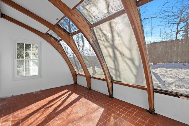 unfurnished sunroom featuring vaulted ceiling with skylight