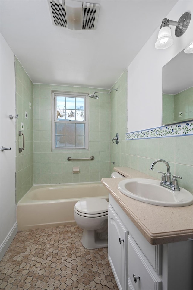 bathroom featuring visible vents, toilet, tile patterned floors, vanity, and tile walls