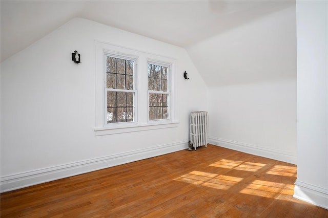 bonus room featuring lofted ceiling, radiator, baseboards, and wood finished floors