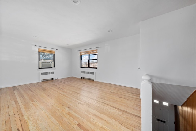 empty room with baseboards, light wood-style flooring, and radiator heating unit