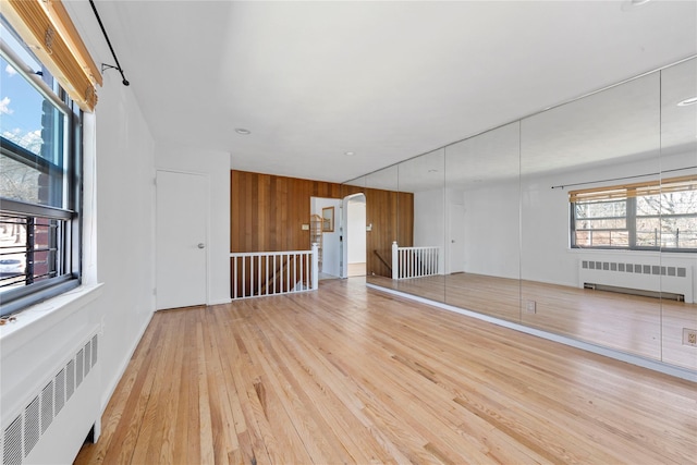 spare room with arched walkways, radiator heating unit, and wood finished floors