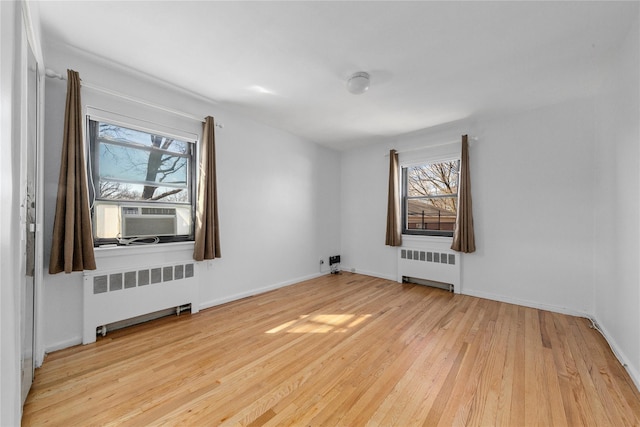 spare room featuring wood finished floors, radiator heating unit, cooling unit, and baseboards