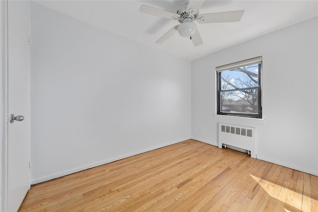 spare room with ceiling fan, radiator heating unit, and hardwood / wood-style flooring