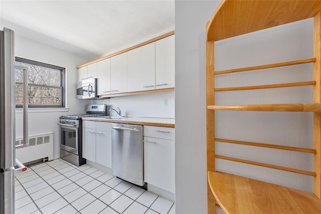 kitchen featuring stainless steel appliances, light countertops, white cabinetry, and radiator heating unit