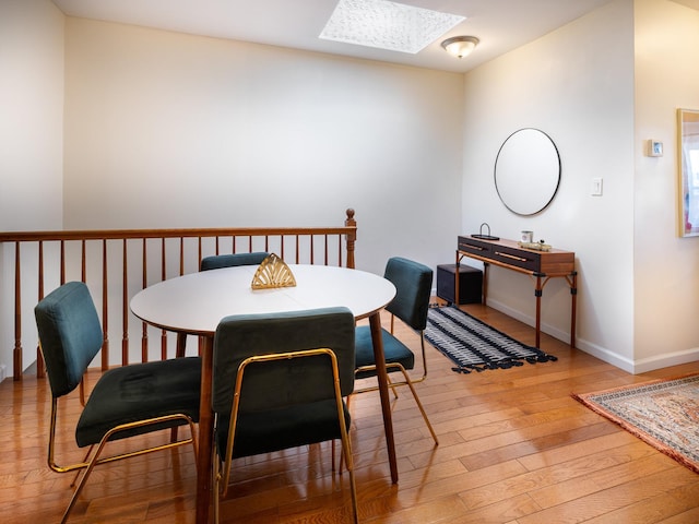 dining area with wood-type flooring and a skylight