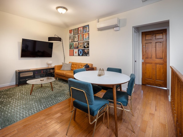 dining space with wood-type flooring and a wall unit AC