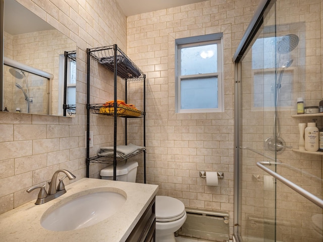 bathroom featuring vanity, toilet, a shower with shower door, and tile walls