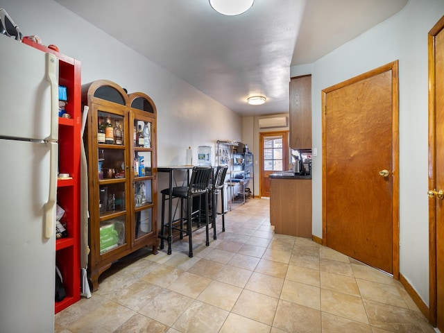 interior space with white fridge, a wall mounted AC, and light tile patterned floors