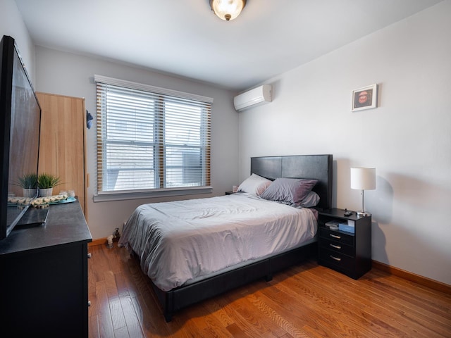 bedroom with a wall mounted air conditioner and dark hardwood / wood-style floors