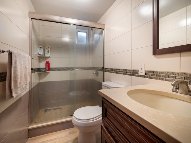 bathroom featuring tile walls, vanity, tasteful backsplash, a shower with shower door, and toilet