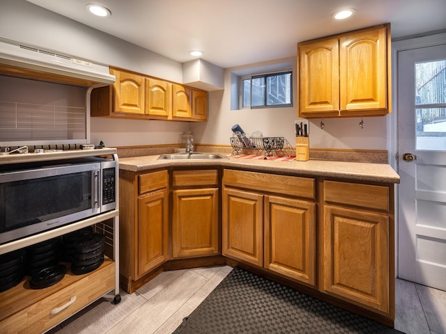 kitchen featuring ventilation hood, sink, and light wood-type flooring