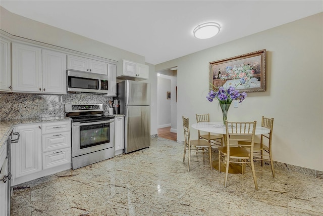 kitchen featuring white cabinetry, appliances with stainless steel finishes, light stone counters, and decorative backsplash