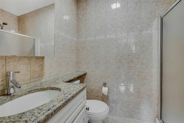 bathroom featuring tile walls, vanity, a shower with shower door, and toilet