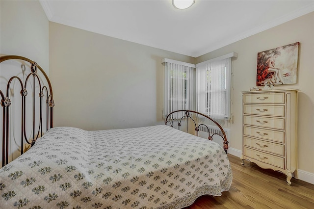 bedroom with crown molding and light hardwood / wood-style floors