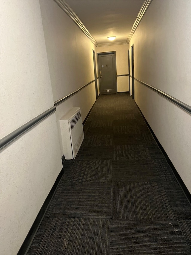 corridor with ornamental molding, radiator, and dark colored carpet