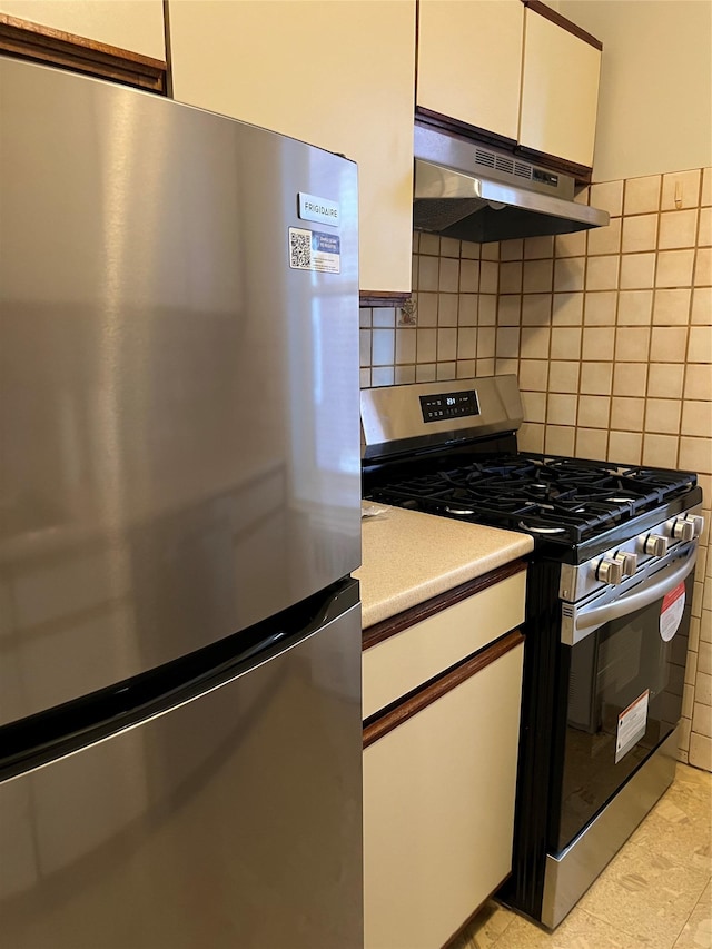 kitchen with stainless steel appliances, white cabinetry, and backsplash