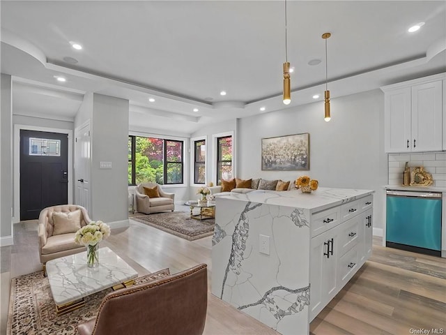 kitchen with white cabinets, light hardwood / wood-style floors, stainless steel dishwasher, and decorative light fixtures