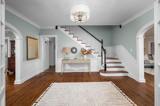 entryway with arched walkways, ornamental molding, wood finished floors, and stairs