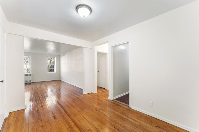 empty room with hardwood / wood-style flooring and radiator