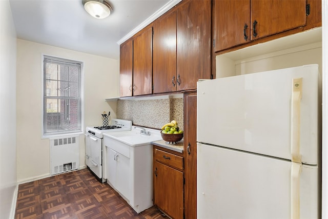 kitchen featuring radiator, dark parquet floors, tasteful backsplash, sink, and white appliances