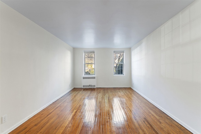 empty room with hardwood / wood-style flooring and radiator heating unit